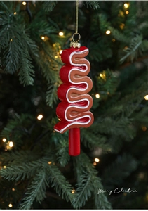Close-up of S-shaped gingerbread ornament with cream swirl hanging on a Christmas tree