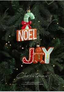 Detail of NOEL and JOY Christmas hanging ornaments with gingerbread man on a festive tree