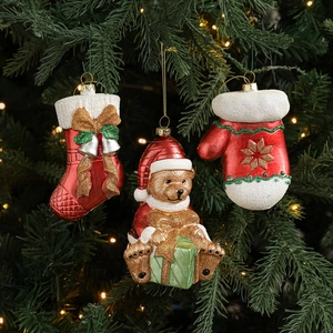 Three festive Christmas tree ornaments featuring a Santa bear, red sock, and glitter mitten