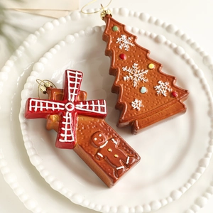 Gingerbread man and tree hanging ornaments with colorful dots on a white plate