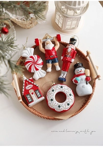 Detalle de 6 colgantes navideños con Papá Noel y Cascanueces en una bandeja de mimbre