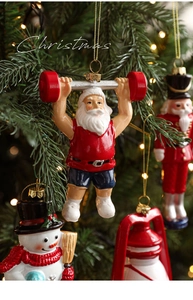 Detalle de Papá Noel levantando pesas colgado en un árbol de Navidad con luces