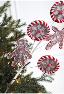 Close-up of a gingerbread man and peppermint candy pick on a lit Christmas tree