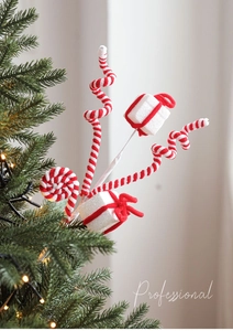 Close-up of candy cane striped gift box and lollipop ornaments on a lighted Christmas tree