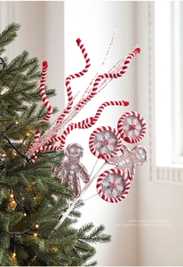 Close-up of gingerbread man and snowflake lollipop picks on a lighted Christmas tree