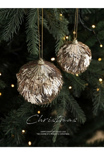 Close-up of champagne gold glitter Christmas ball ornament hanging on a festive tree branch