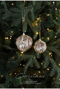 Close-up of champagne gold glitter Christmas balls hanging on a festive tree with warm lights