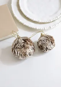 Close-up of two champagne gold glitter tassel ornaments with shiny metallic textures
