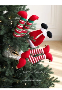 Detailed view of striped elf legs with gold bells tucked into a festive Christmas tree