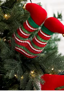 Detail of Christmas elf legs with bells and glitter stripes on a festive tree branch