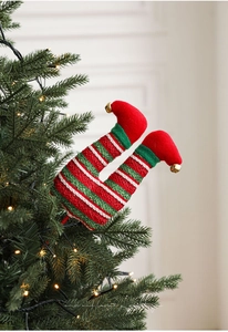 Close-up of Christmas elf leg pick with red and green stripes and gold bell on a tree