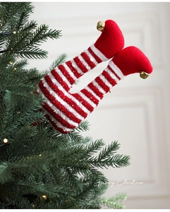 Detail of plush Christmas elf leg sticks with red striped socks and gold bells on tree