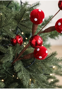 Detail of red velvet mushroom picks and glossy baubles on a Christmas tree branch