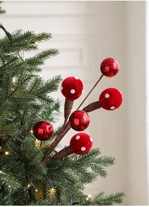 Close-up of red foam ball and polka dot mushroom picks on a green Christmas tree
