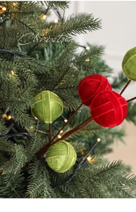 Detail of red and green velvet Christmas ornaments on a stem with festive bokeh background