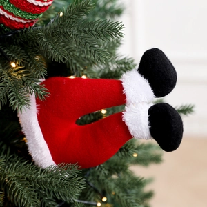 Christmas elf leg decoration inserted into tree branches with festive warm lighting
