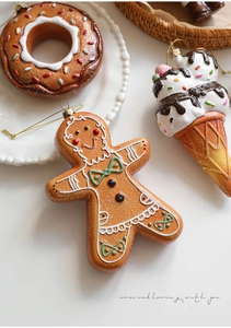 Detailed view of gingerbread man and donut resin ornaments with gold hanging strings