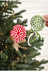 Detail of hand-knitted Christmas candy cane lollipop with burlap bow on festive tree