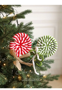 Close-up of plush candy cane lollipops with burlap bows on a lit Christmas tree
