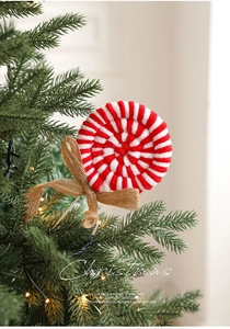 Close-up of red and white candy cane lollipop plush ornament with burlap bow on tree