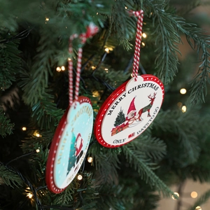 Two wooden Christmas countdown ornaments with reindeer and gnome on a lit pine tree