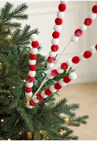 Détail de tiges de Noël avec boules en peluche rouges et blanches et effet de neige