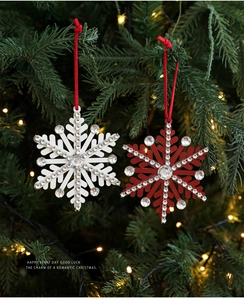 Christmas snowflake ornaments with rhinestones hanging on a pine tree branch