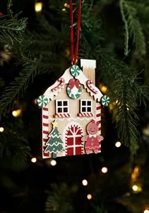 Detail of a painted wooden gingerbread house Christmas ornament with red silk ribbon