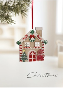 Detail of red wooden gingerbread house ornament hanging on a pine branch for Christmas