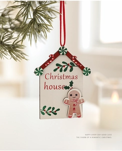Close-up of a wooden Christmas house ornament with gingerbread man hanging on pine branch