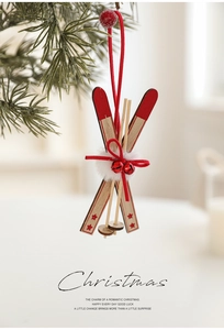 Close-up of wooden ski ornament with red bells and stars hanging on a Christmas tree