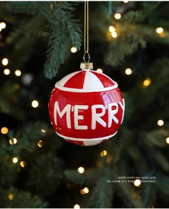 Nahaufnahme einer rot-weiß gestreiften Weihnachtskugel mit Merry-Schriftzug am Baum