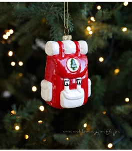 Detail eines rot-weißen Rucksack-Weihnachtsanhängers mit Baummotiv auf festlichem Baum