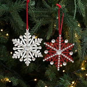 Red and white snowflake Christmas tree ornaments with rhinestones hanging on pine branches
