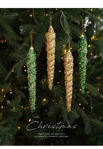 Close-up of glittery gold and green spiral icicle ornaments on a glowing Christmas tree