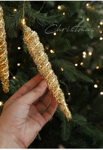 Close-up of golden spiral icicle ornament with glitter on a bokeh Christmas tree