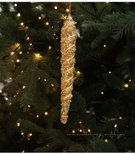 Detailed view of a golden icicle Christmas ornament with sequins on a festive tree branch