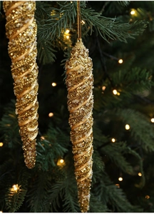 Detail view of golden spiral icicle ornaments with glitter hanging on a Christmas tree