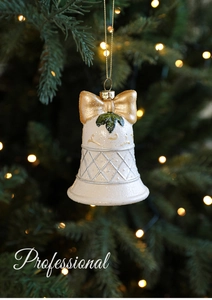 Gros plan d'une cloche de Noël crème avec un nœud doré et du houx sur un sapin