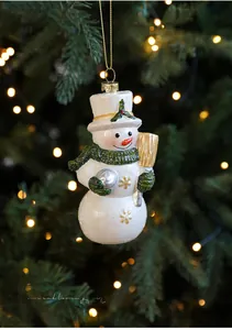 Détail d'un ornement de bonhomme de neige avec écharpe verte sur sapin de Noël illuminé