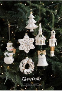 Détail de suspensions de Noël blanches et dorées sur un sapin vert festif