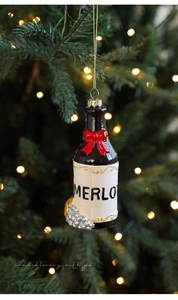 Détail d'un ornement bouteille de vin Merlot avec nœud rouge sur sapin de Noël vert
