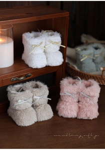 Close-up van zachte pluche babylaarzen met glitterstrikjes in vier kleuren