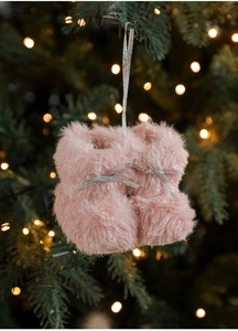 Detail van roze pluche kerstlaarzen met zilveren strikken aan een verlichte boom