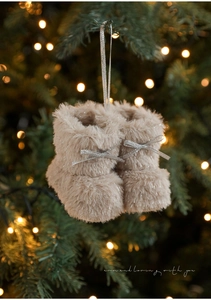 Detail van beige pluizige pluchen kerstlaarsjes die aan een verlichte boom hangen