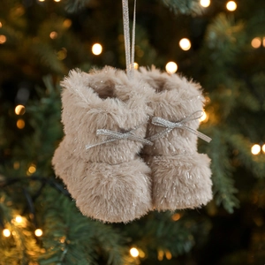 Paar beige pluchen kerstlaarsjes met zilveren strikken hangend in een feestelijke boom