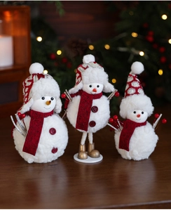 Three plush Christmas snowmen set with red scarves on a festive wooden table display