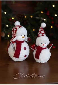 Detail of plush Christmas snowmen with red knit hats and scarves on wooden table