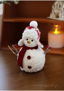 Detail of plush snowman ornament with red knit hat, scarf and branch arms for Christmas decor