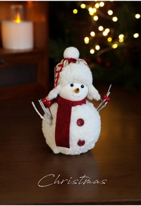 Detailed close-up of a plush Christmas snowman doll with a red scarf and branch arms